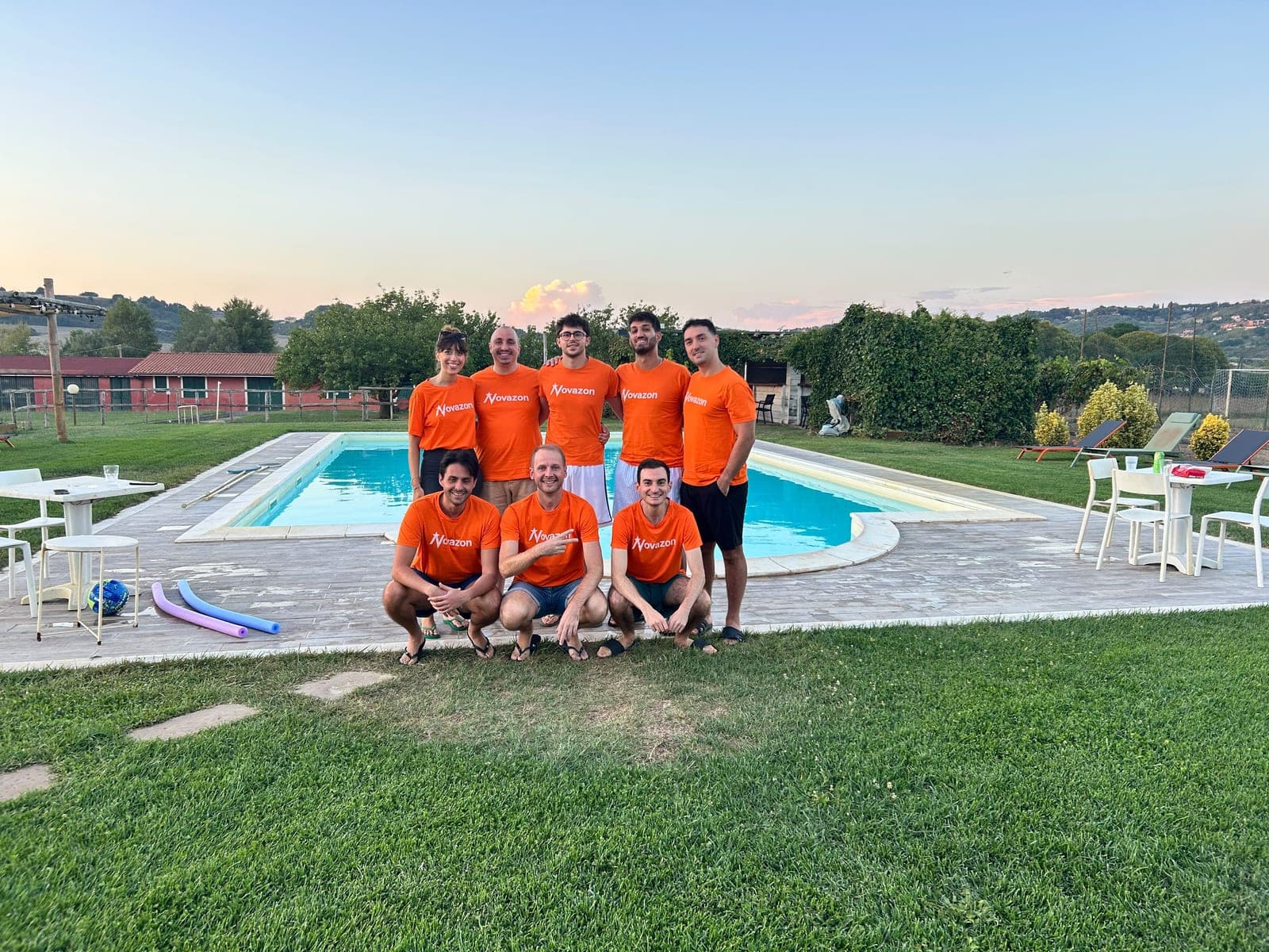 Il team Novazon al completo, in piscina al tramonto, con le magliette arancioni